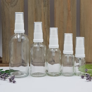 Peut inclure: Cinq flacons en verre transparent avec des pompes blanches. Les flacons sont disposés par ordre de taille, du plus grand au plus petit. Les flacons sont vides et ont une surface lisse et transparente.