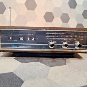 May include: Vintage brown and silver radio with a digital clock display showing 10:13. The radio has a wooden frame, chrome knobs, and a telescoping antenna. The text "Sleepwatch Radio" is visible.