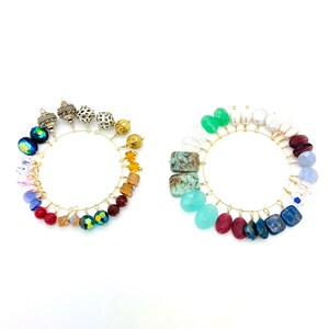 May include: Two circular arrangements of colorful beads and gemstones on gold wire. The left arrangement features a spectrum of colors, including blue, red, and yellow beads. The right arrangement showcases green, turquoise, and red gemstones.