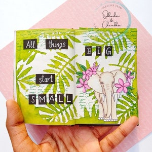 May include: A small, open book with green leaves and a white elephant illustration. The text "All things start small" and "BIG" is written in black on white paper squares.