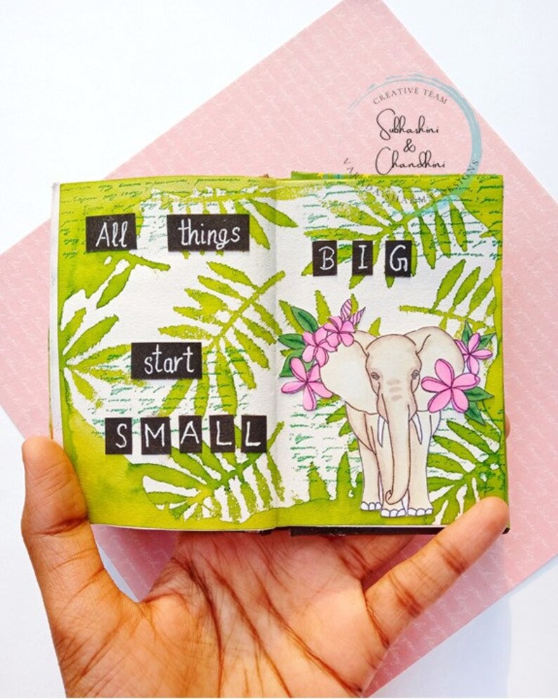 May include: A small, open book with green leaves and a white elephant illustration. The text "All things start small" and "BIG" is written in black on white paper squares.