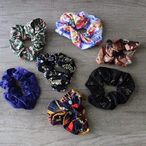 May include: Eight colorful scrunchies with various patterns, including tie-dye, Harry Potter, and holiday designs.