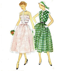 May include: Two women wearing sleeveless dresses. The woman on the left is wearing a pink dress with a white collar and a white belt. The woman on the right is wearing a green plaid dress with a white collar and a black belt. Both women are wearing white gloves and white shoes.