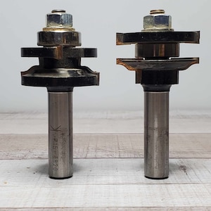 May include: Two router bits with black and silver metal bodies. The bit on the left has a label that reads "K-P15-3820".