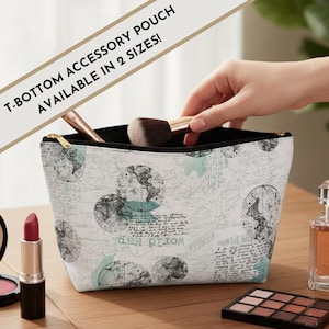 May include: A white T-bottom accessory pouch with a world map design, featuring black and teal accents. The pouch has a gold zipper and is open, revealing makeup brushes. Text on the pouch reads "WORLD MAP".