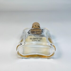 Pu&ograve; includere: Una bottiglia di vetro trasparente di lozione dopobarba Stetson con tappo color oro. La bottiglia ha una forma rettangolare con bordi arrotondati e contiene un liquido color ambra chiaro. L'etichetta recita "After Shave Lotion" e "2.0 FL. OZ."