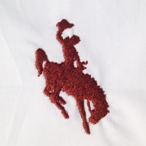 以下が含まれることがあります： 白い背景に、茶色の刺繍で描かれた、馬が跳ね上がっている様子と、その上に乗っているライダーの画像です。