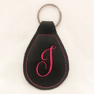 May include: Black leather keychain with a pink embroidered letter "J" and a silver key ring.
