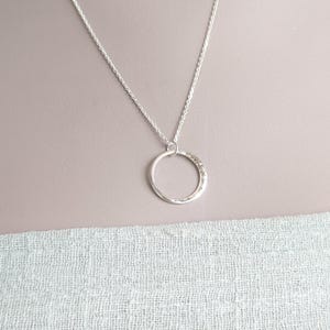 May include: A silver chain necklace with a hammered circle pendant.