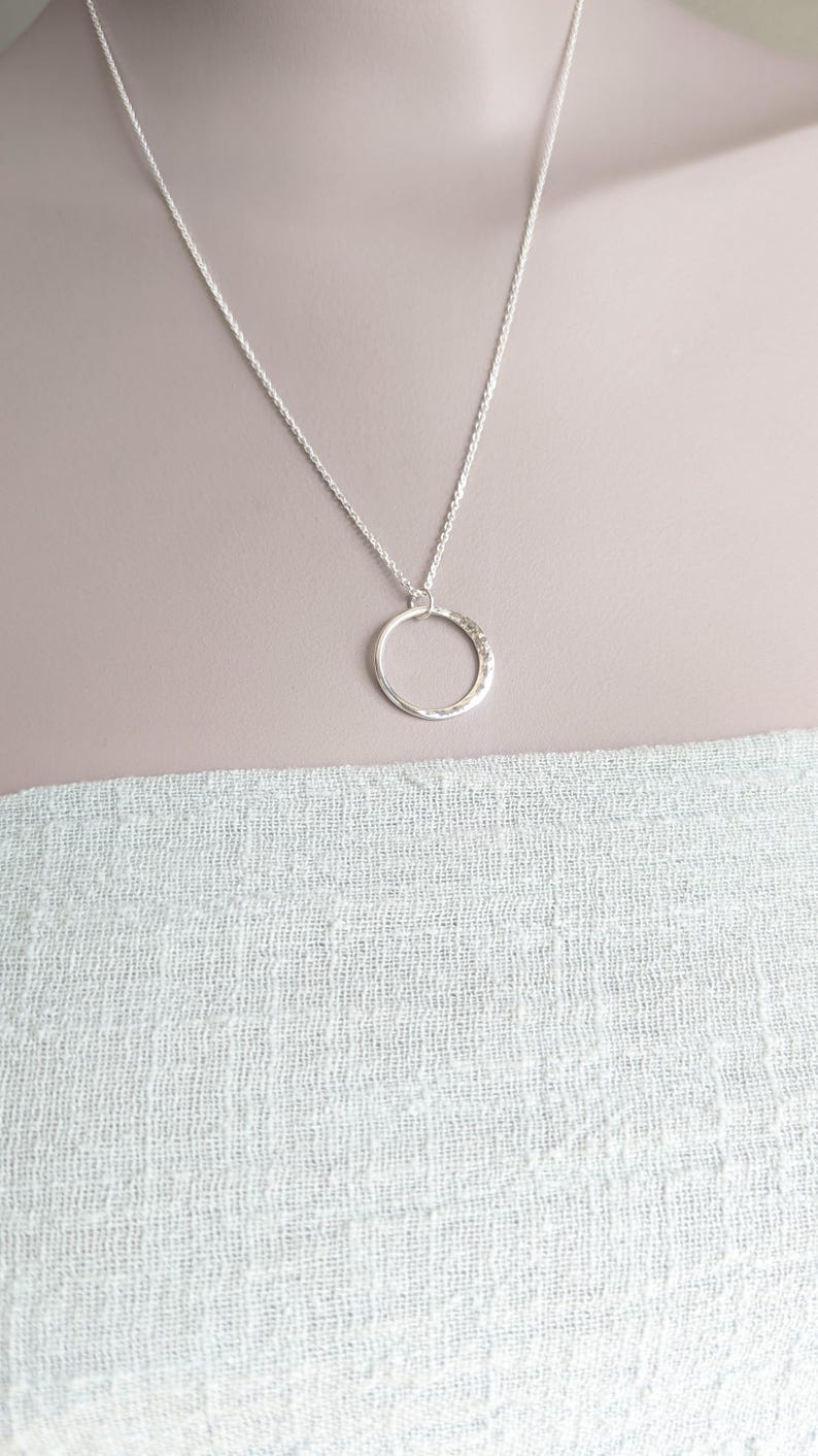 May include: A silver chain necklace with a hammered circle pendant.