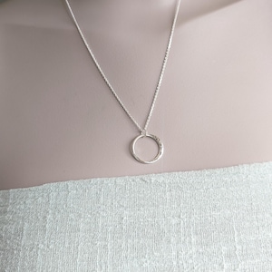 May include: A silver chain necklace with a hammered circle pendant.