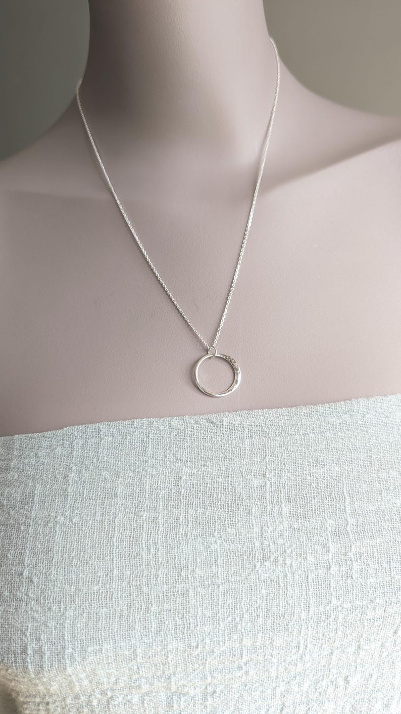 May include: A silver chain necklace with a hammered circle pendant.