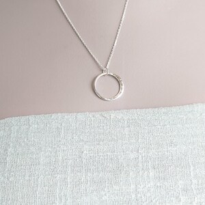 May include: A silver chain necklace with a hammered circle pendant.