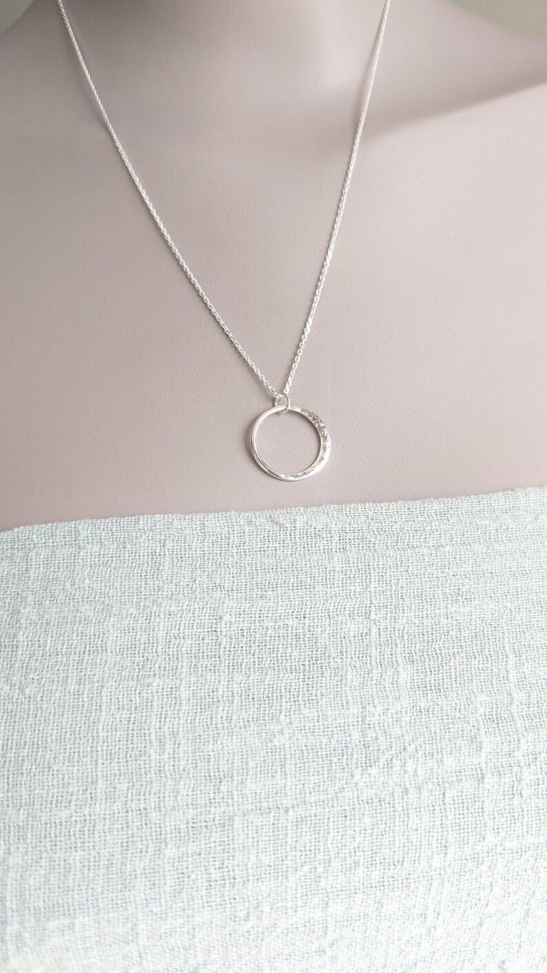 May include: A silver chain necklace with a hammered circle pendant.
