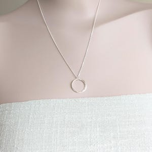 May include: A silver chain necklace with a hammered circle pendant.