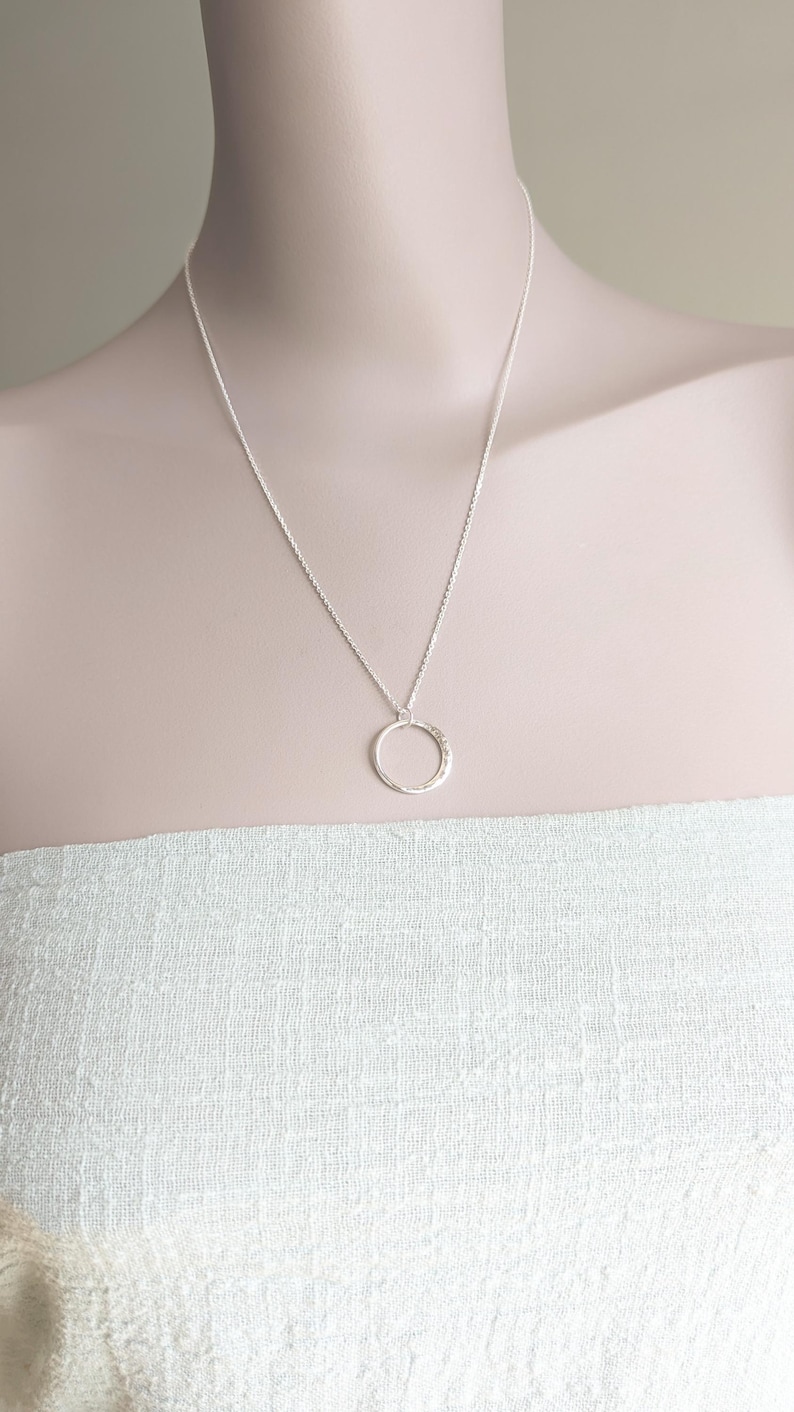 May include: A silver chain necklace with a hammered circle pendant.