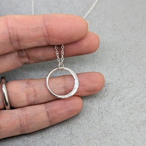 May include: A silver chain necklace with a hammered circle pendant.