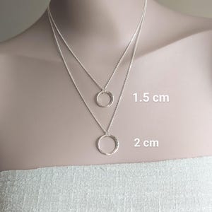 May include: Two silver necklaces with hammered circle pendants. The smaller pendant is 1.5 cm in diameter and the larger pendant is 2 cm in diameter.