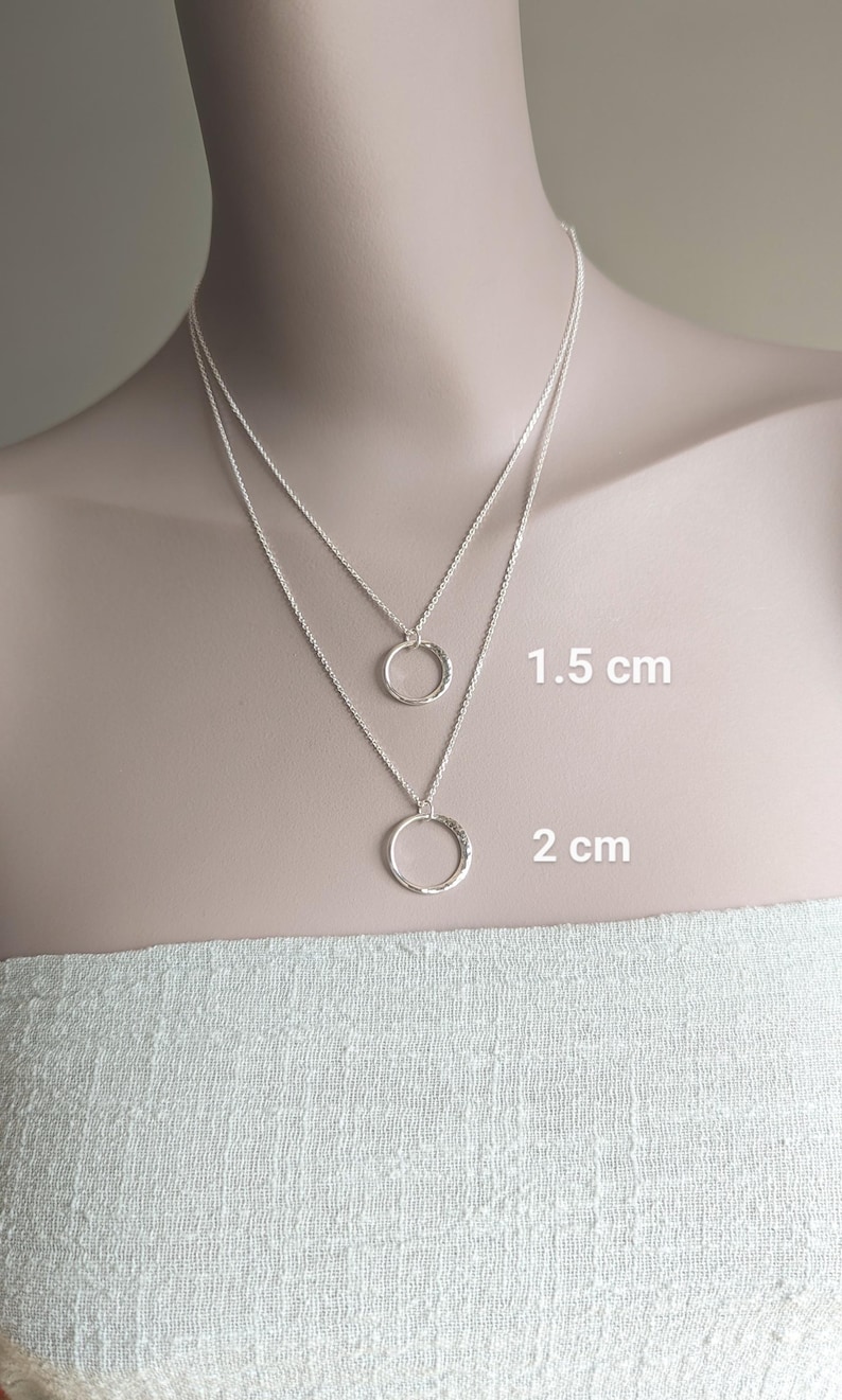 May include: Two silver necklaces with hammered circle pendants. The smaller pendant is 1.5 cm in diameter and the larger pendant is 2 cm in diameter.