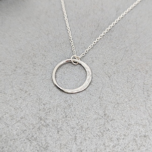 May include: A silver chain necklace with a hammered circle pendant.