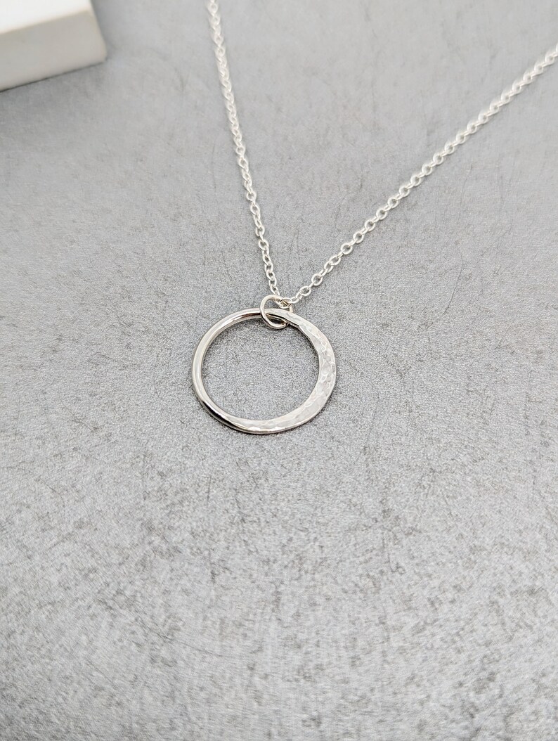 May include: A silver chain necklace with a hammered circle pendant.