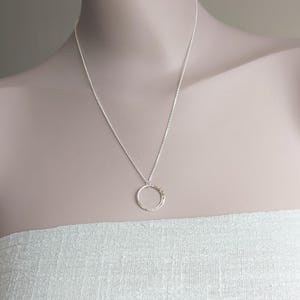 May include: A silver chain necklace with a hammered circle pendant.