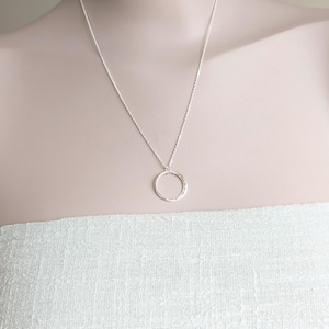 May include: A silver chain necklace with a hammered circle pendant.