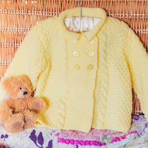 Aran Baby Double Brested Jacket, Hand Knitted In Soft Acrylic Baby Aran Yarn. In Gender Neutral Lemon / Pale Yellow, Approx 1 Year Size
