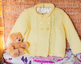 Aran Baby Double Brested Jacket, Hand Knitted In Soft Acrylic Baby Aran Yarn. In Gender Neutral Lemon / Pale Yellow, Approx 1 Year Size