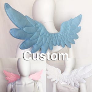 May include: Three pairs of felt angel wings in different colours: light blue, white and pink. The wings are attached to a white felt strap that can be worn around the neck.