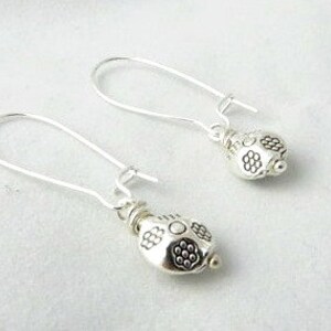 May include: A pair of silver dangle earrings with a small, round, textured bead at the end of each earring.