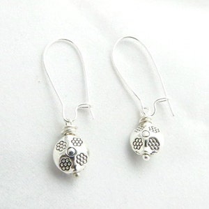May include: A pair of silver dangle earrings with a round, textured bead at the end of each earring.