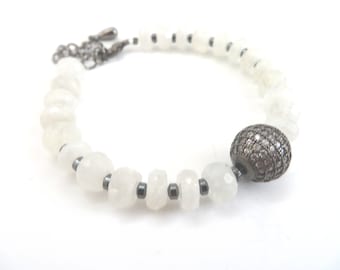 May include: A white gemstone bracelet with a silver clasp and a silver bead accented with small diamonds.
