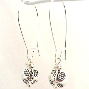 May include: A pair of silver dangle earrings with a floral design. The earrings are made of metal and have a simple, elegant design.