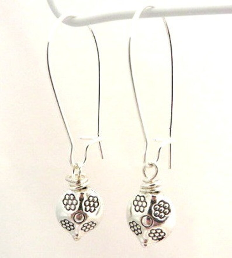 May include: A pair of silver dangle earrings with a floral design. The earrings are made of metal and have a simple, elegant design.