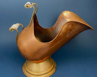Può includere: Un secchio per carbone in rame con una base in ottone e due manici in porcellana bianca. Il secchio ha la forma di una paletta e un design curvo.