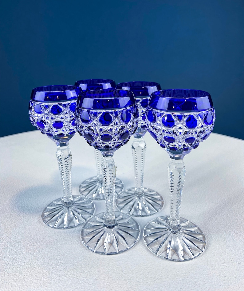 Puede incluir: Juego de cinco vasos de cristal azul cobalto con dise&ntilde;o de cristal tallado. Los vasos tienen una copa redonda y un tallo largo y delgado.
