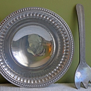 May include: A silver serving dish with a beaded rim and a matching silver serving fork.