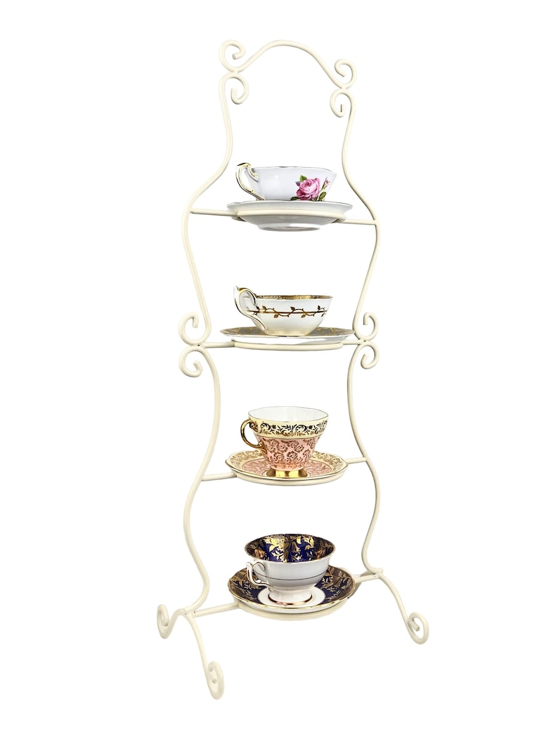 May include: White metal teacup stand with four tiers. Each tier holds a delicate teacup and saucer with floral and gold designs.
