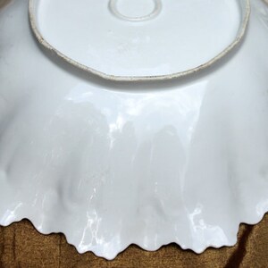 May include: White porcelain bowl with a scalloped edge. The bowl is plain white with no markings or designs.