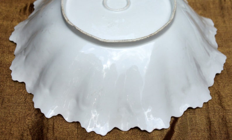 May include: White porcelain bowl with a scalloped edge. The bowl is plain white with no markings or designs.