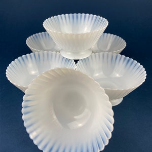 May include: Set of six white opalescent glass bowls with blue trim. The bowls have a scalloped edge and a fluted design.