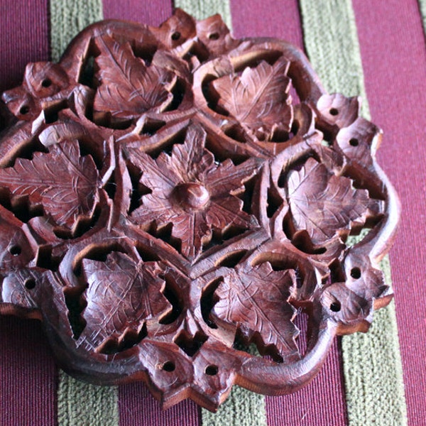 Coaster. Hand carved in teak wood.  It has four short legs.