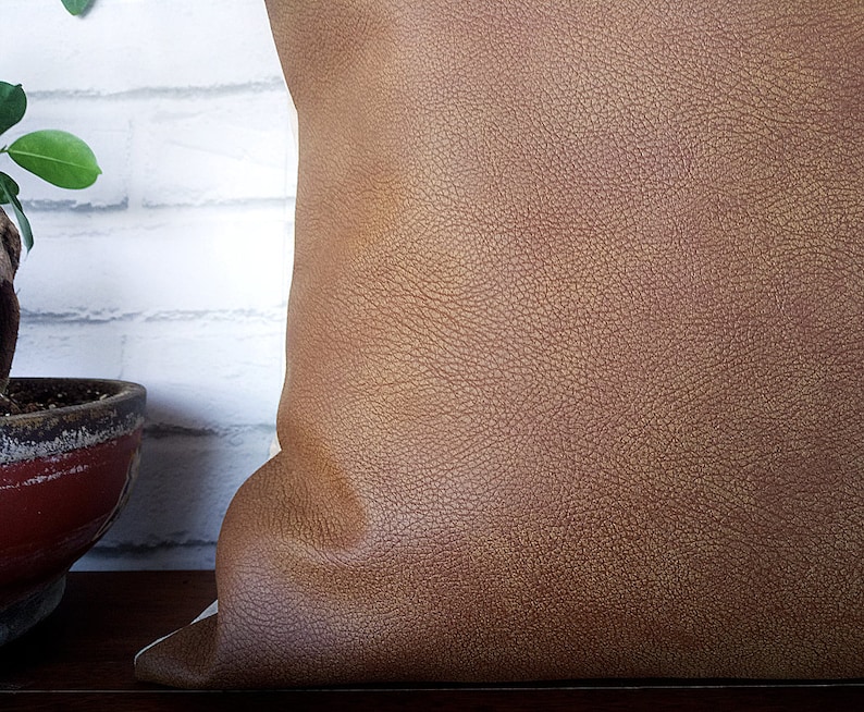 May include: A brown leather pillow with a textured surface.