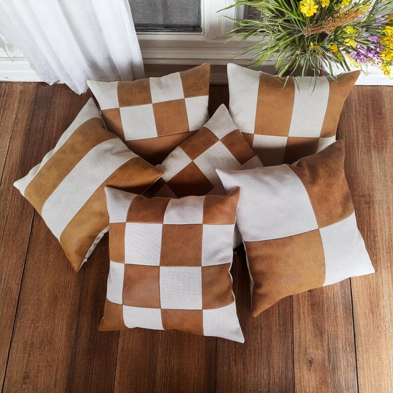 May include: Six decorative throw pillows with a checkered pattern in brown and white. The pillows are made of a combination of faux leather and fabric.