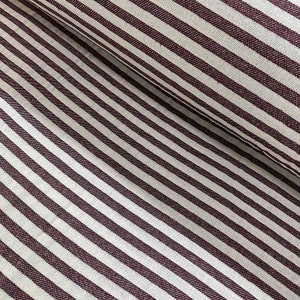May include: White and burgundy striped fabric with a subtle texture. The fabric is woven with thin stripes of burgundy against a white background.