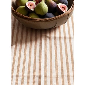 May include: A brown and white striped tablecloth with a bowl of fresh figs in the center.
