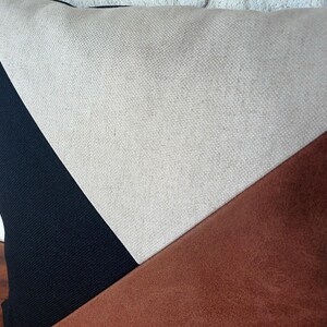 May include: A decorative pillow with a geometric design. The pillow features a black, beige, and brown color scheme. The pillow is made of a textured fabric and has a modern aesthetic.