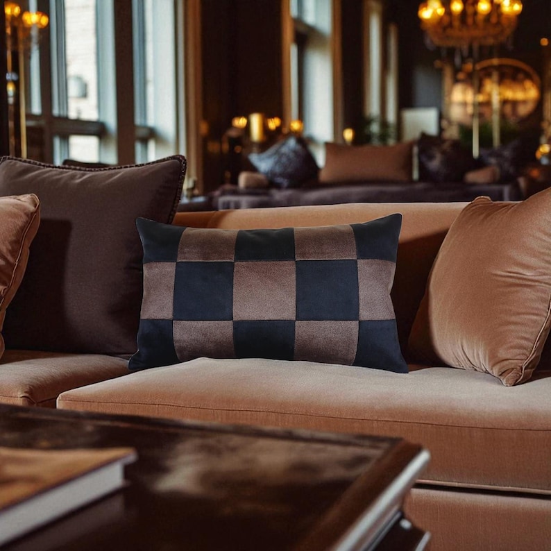 Puede incluir: Un coj&iacute;n rectangular decorativo con un patr&oacute;n de tablero de ajedrez en tonos marr&oacute;n y negro. El coj&iacute;n est&aacute; colocado sobre un sof&aacute; color melocot&oacute;n, con otros cojines en diferentes tonos de marr&oacute;n. La escena se desarrolla en un espacio vital acogedor y bien iluminado.