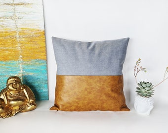 Funda de almohada de piel sintética color camel, con detalles en algodón azul claro.